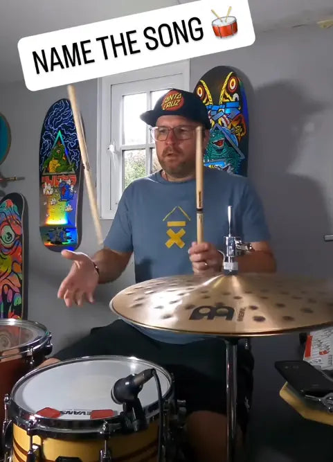 Tom Howarth wearing a blue Above Average drummer ascent logo while he's doing stick tricks