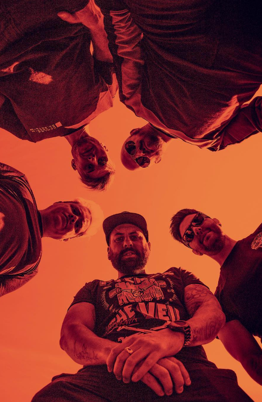 All members of Catalysts stood over the camera looking down with an orange sunset filter across the photo