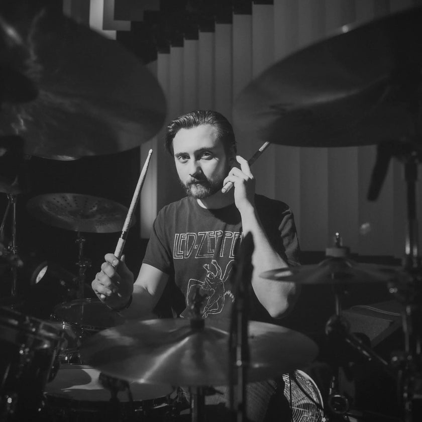 black and white image of Nic Collins, Above Average endorser, sat behind a drum kit, sticks in hand