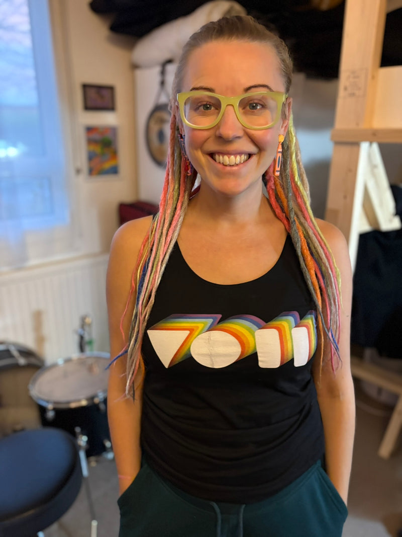 drummer and percussionist vicky o neon wearing a vest from Above Average Clothing featuring her own rainbow VON logo