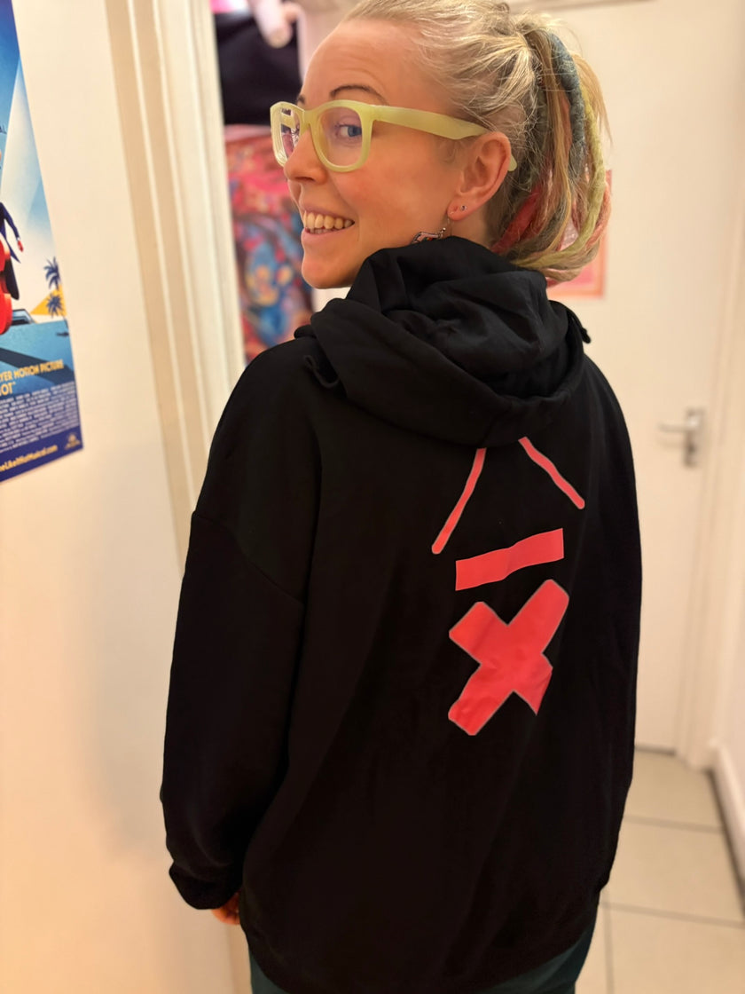 vicky o neon wearing her above average clothing zip up hoodie with a bright pink drummer logo on the back